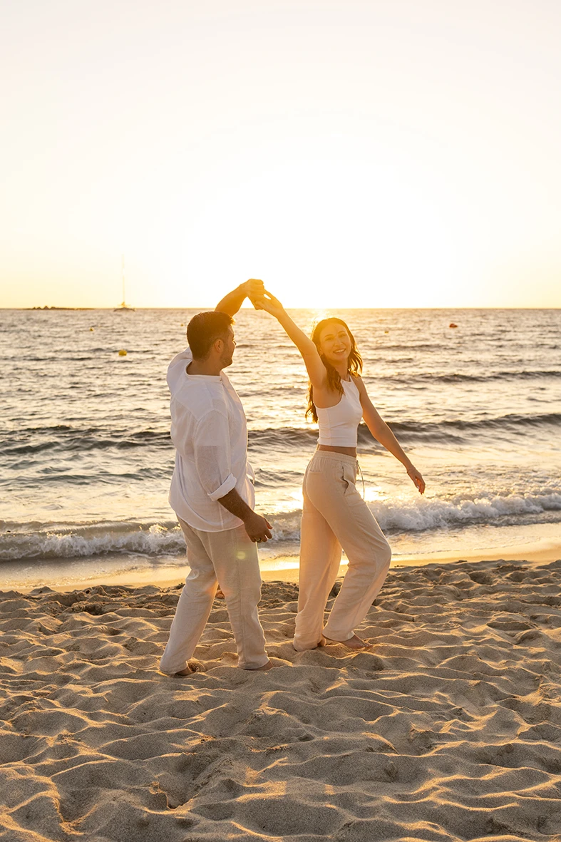 Pareja bailando en la orilla del mar al atardecer durante una sesión con fotógrafo en Mallorca