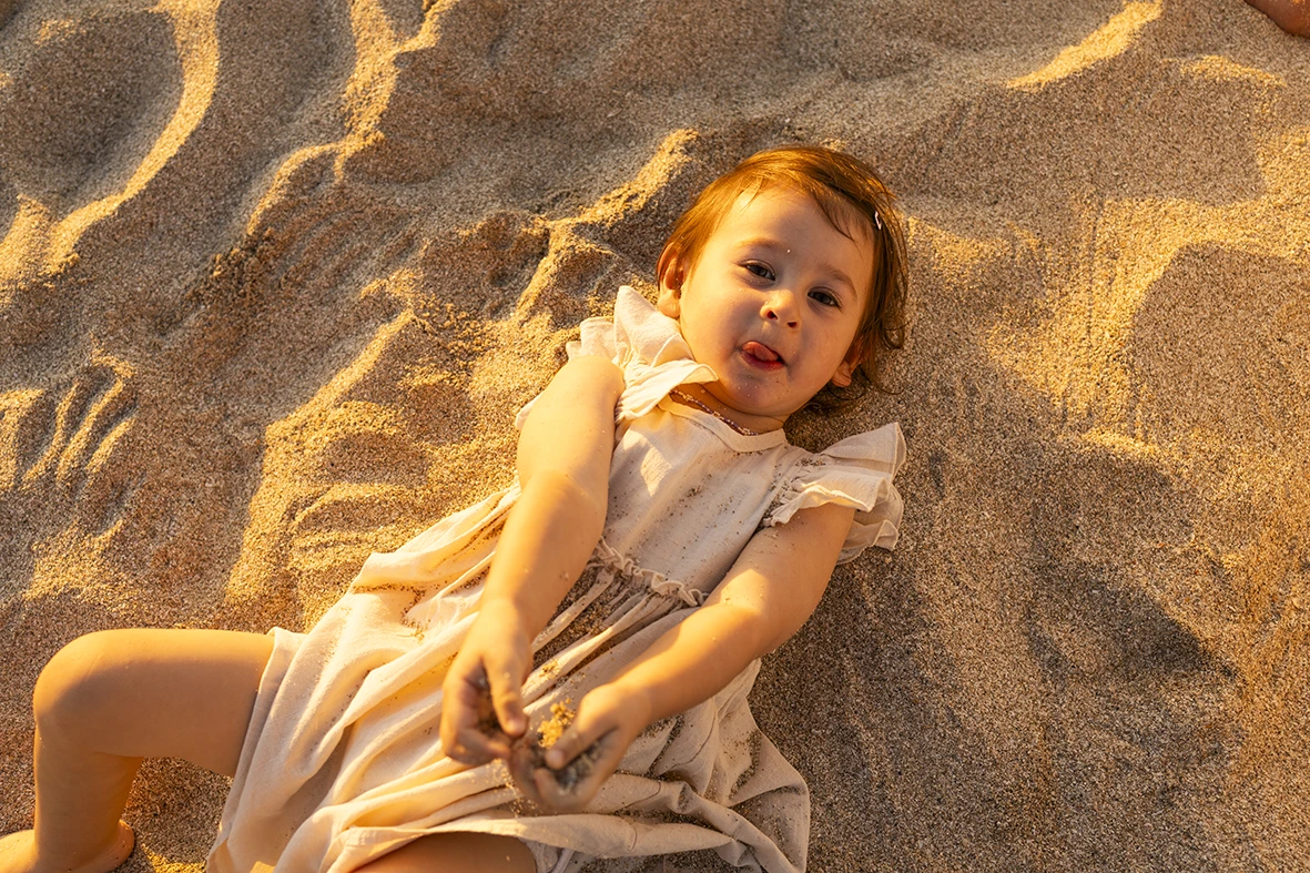 Niña jugando en la arena durante una tarde dorada en una sesión de fotografía de familias en Mallorca