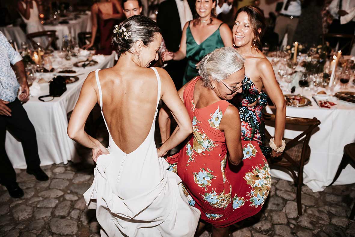 Novia bailando con invitadas durante la fiesta de su boda en Mallorca, fotografía espontánea y alegre.