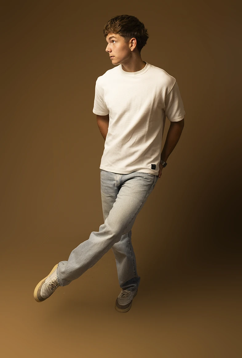 Male model with casual look in studio photoshoot with beige background.
