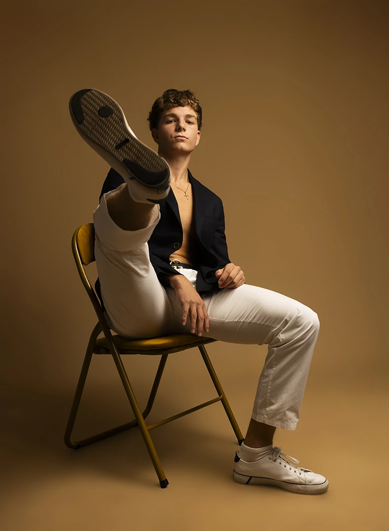 Male model lifts leg toward the camera in creative studio photoshoot.