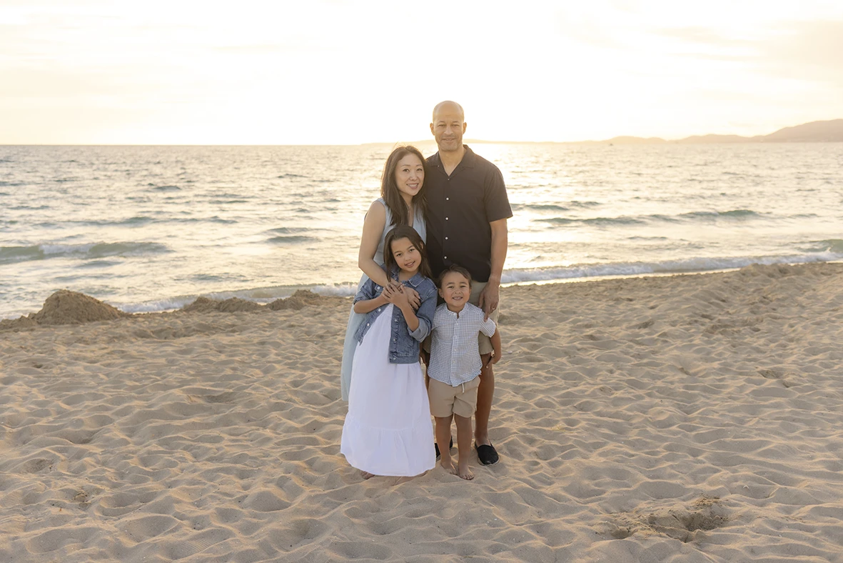 Familia en la playa al atardecer durante sesión de fotos con la fotógrafa Inma del Valle en Mallorca.
