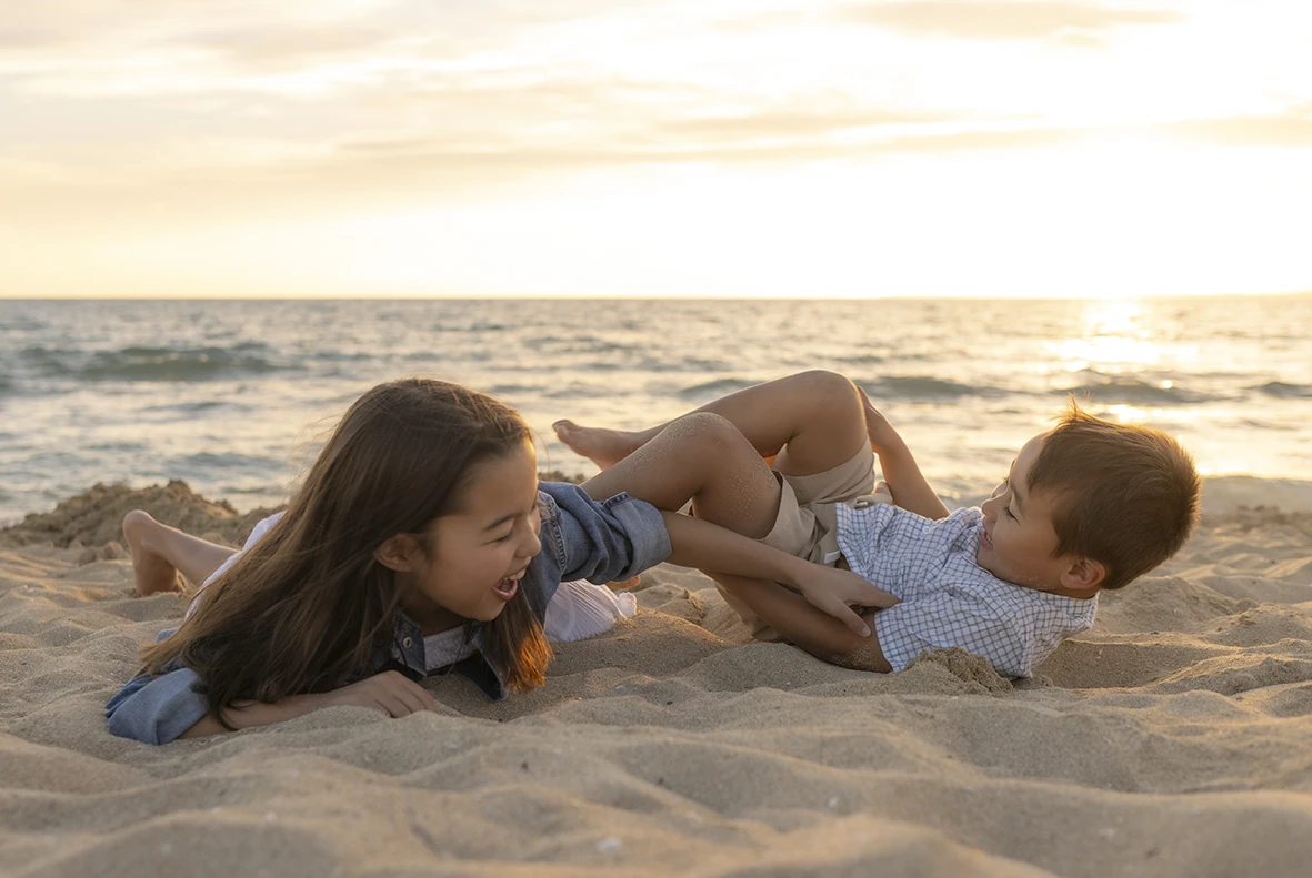 Niños jugando en la arena durante el atardecer en una sesión familiar con Inma del Valle en Mallorca.