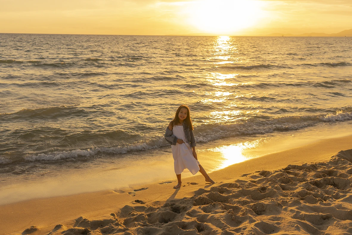 Fotografía de una niña caminando junto al mar durante el atardecer en una playa de Mallorca, tomada por la fotógrafa Inma del Valle.