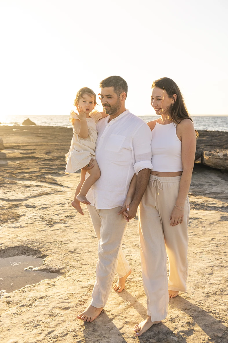 Couple walking with their daughter along the beach at sunset during a family photography session in Mallorca