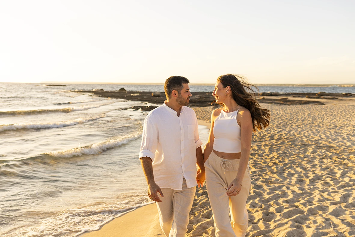 Couple walking along the seashore under the golden sunset light captured by a photographer in Mallorca