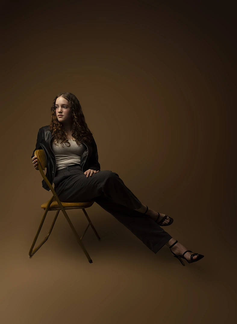 young model seated in a warm toned studio