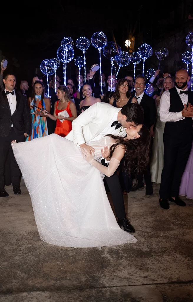 Baile de los novios con beso romántico rodeados de invitados en Son Marroig