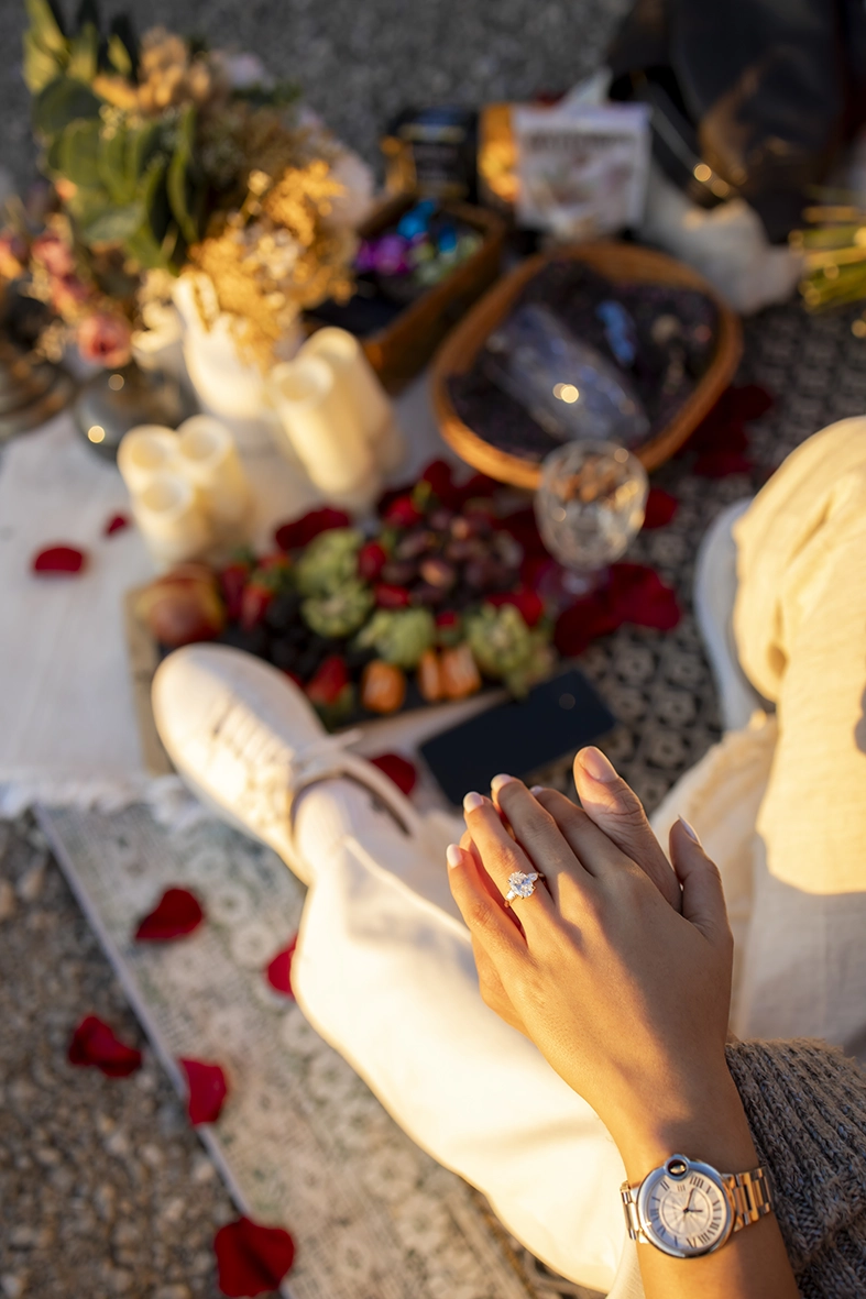 Detalle del anillo durante pedida de mano exclusiva en Mallorca con decoración romántica y pétalos al atardecer.