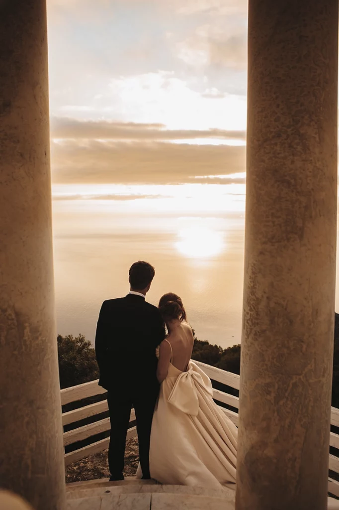 Bride and groom watching sunset between columns at Son Marroig in Mallorca