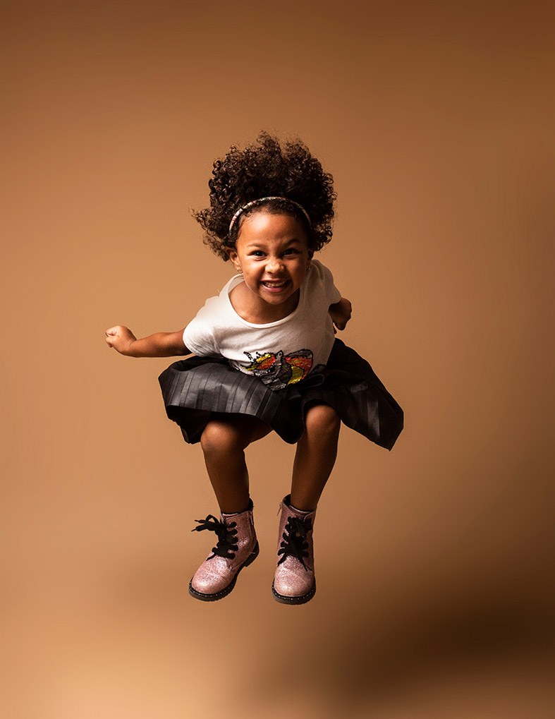 niña saltando con vestido en sesión de fotos