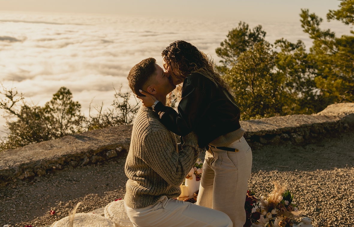 couple kissing after a romantic marriage proposal in Mallorca with sea of clouds sunset view photographed by Inma del Valle