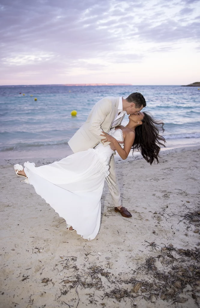 Novios besándose en la playa durante una boda elegante en Mallorca al atardecer, fotografía realizada por Inma del Valle.