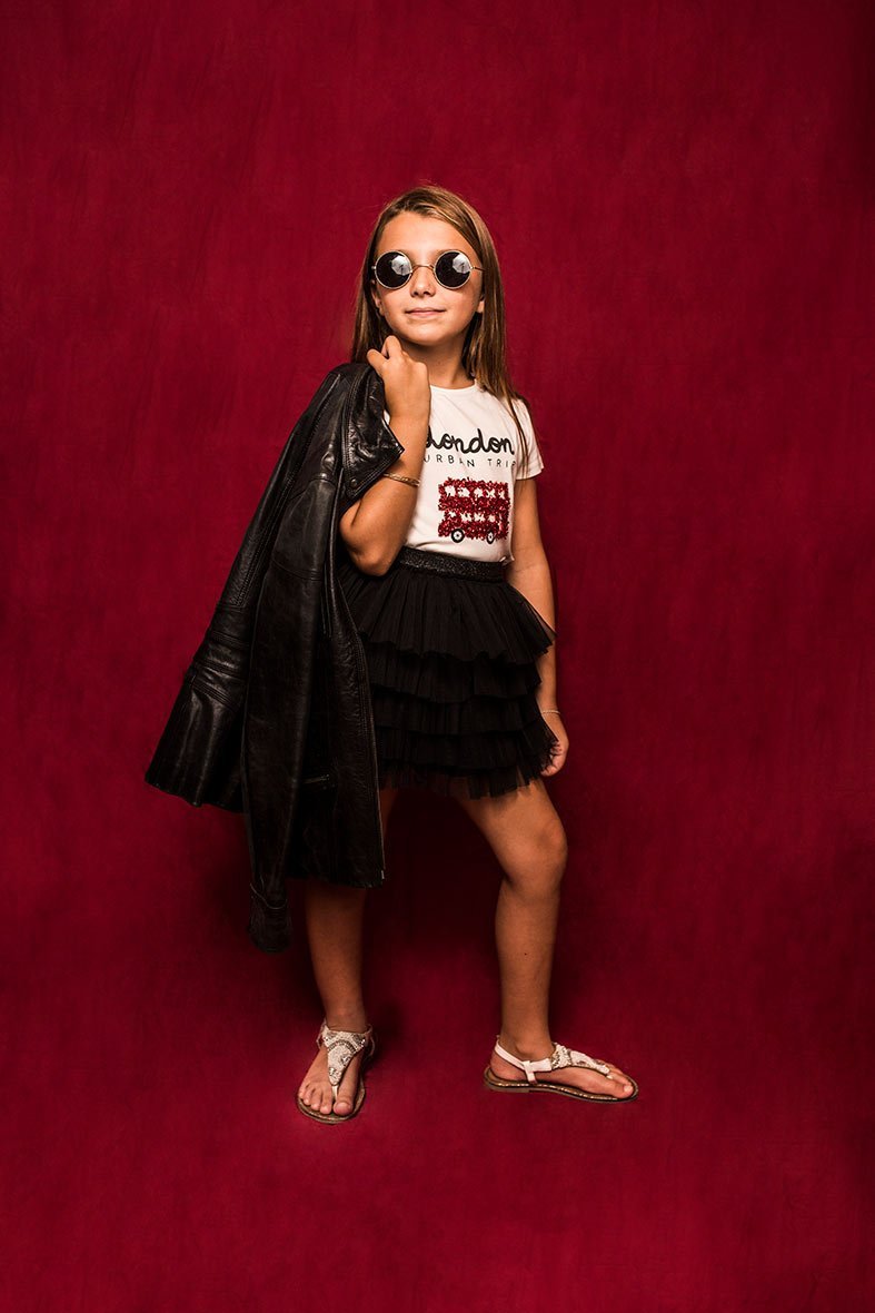 niña posando en estudio con fondo rojo