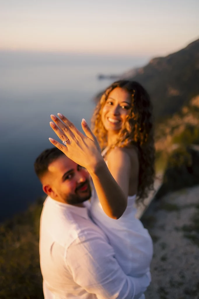 Mujer mostrando su anillo de compromiso mientras su pareja la levanta durante una pedida de mano al atardecer en Mallorca fotografiada por Inma del Valle