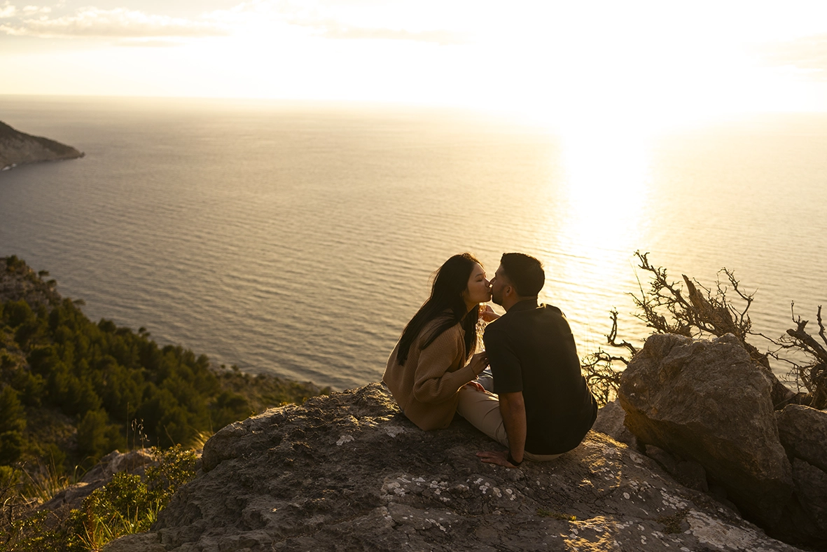 Couple kissing on a cliff at sunset in Mallorca photographed by Inma del Valle, Mallorca cliff proposal photographer