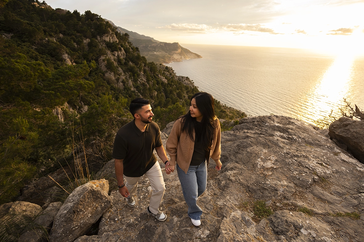 Couple walking together on a cliff in Mallorca during a romantic proposal session photographed by Inma del Valle, Mallorca cliff proposal photographer