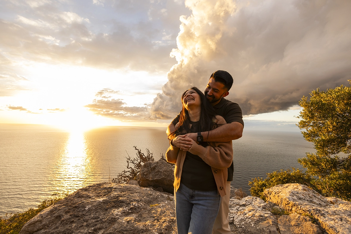 Couple laughing together during a romantic sunset proposal in Mallorca photographed by Inma del Valle, Mallorca cliff proposal photographer