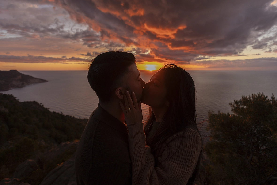 Couple kissing during a dramatic sunset proposal in Mallorca photographed by Inma del Valle, Mallorca cliff proposal photographer