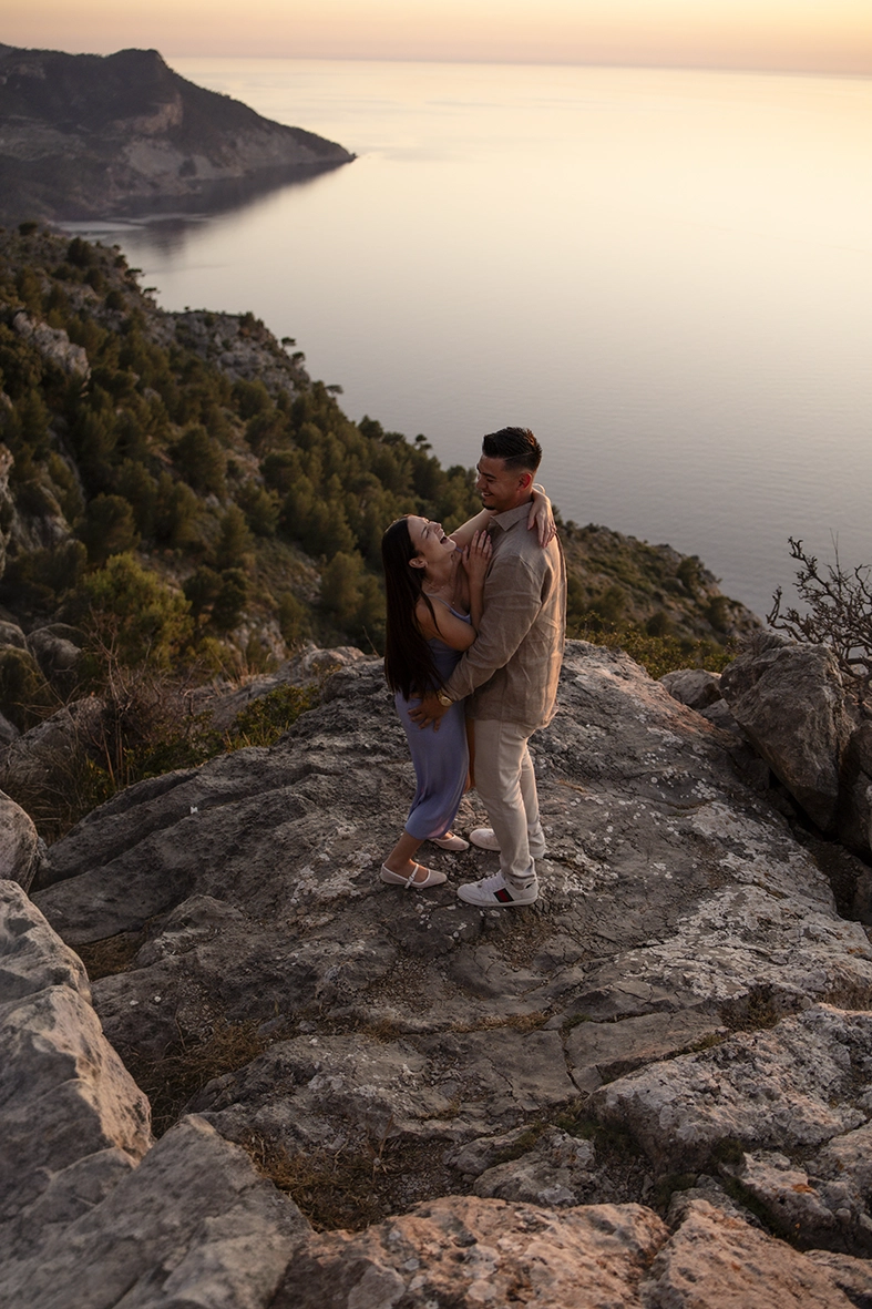Katie y David se abrazan sobre los acantilados de Mallorca durante una romántica sesión de fotos tras su compromiso.