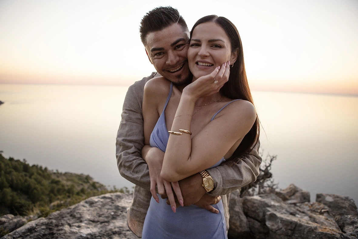 Katie showing her engagement ring while embracing David during a romantic sunset in Mallorca.