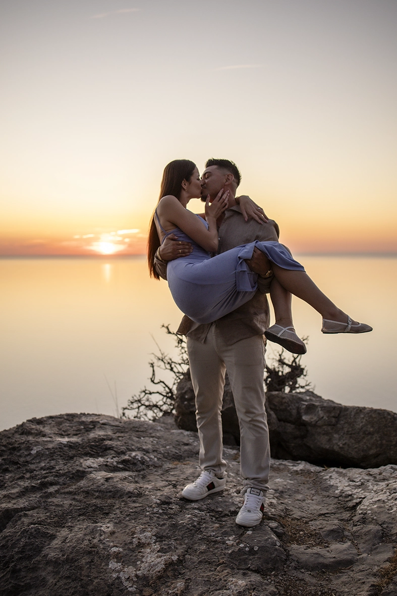 Katie and David share a kiss at sunset after their private proposal in Mallorca overlooking the Mediterranean Sea.