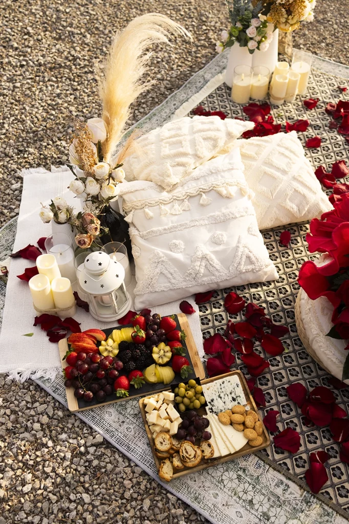 Elegant luxury proposal picnic details in Mallorca with candles, flowers, rose petals and gourmet appetizers during a romantic sunset setup photographed by Inma del Valle.