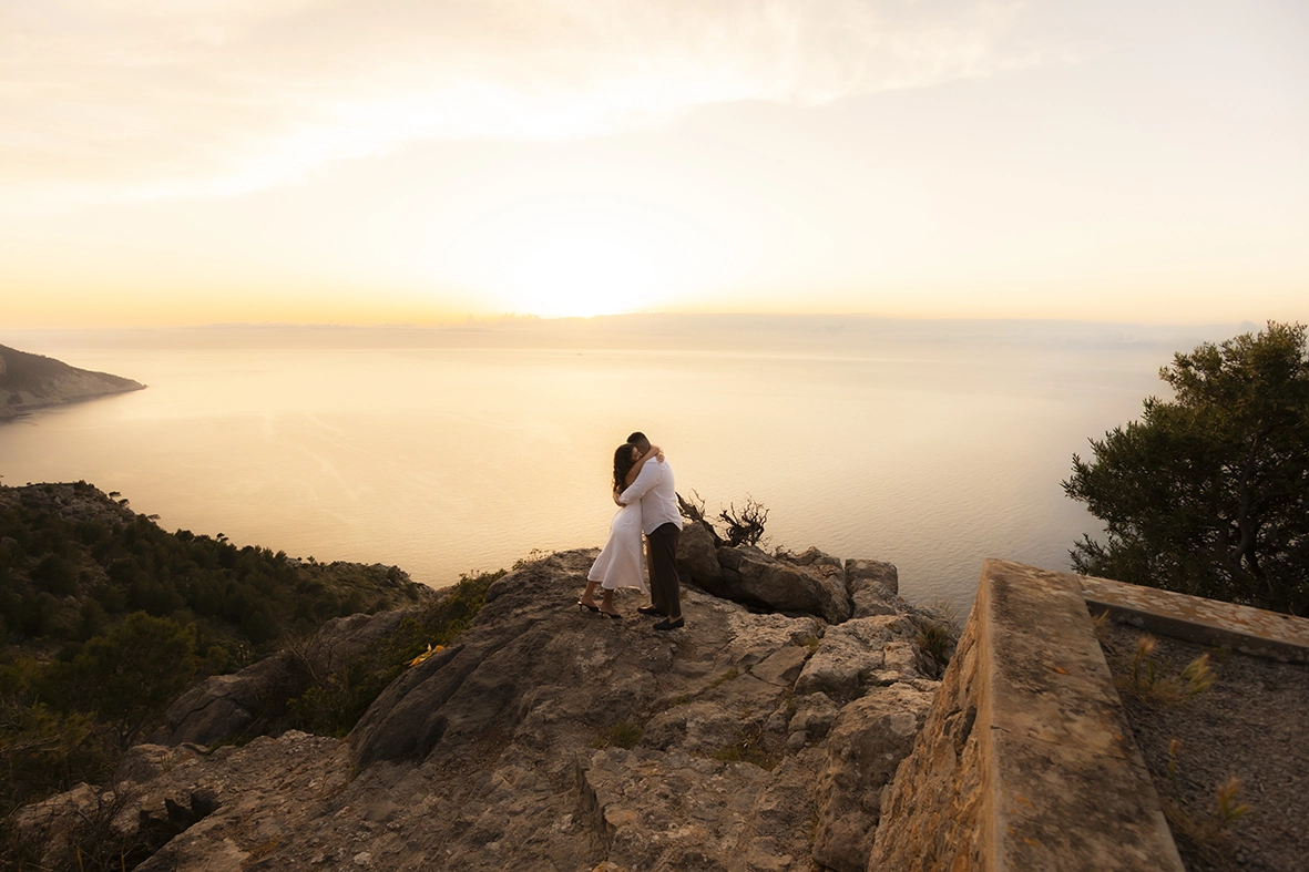 Couple embracing on the cliffs of Mallorca during sunset after a surprise proposal photographed by Inma del Valle