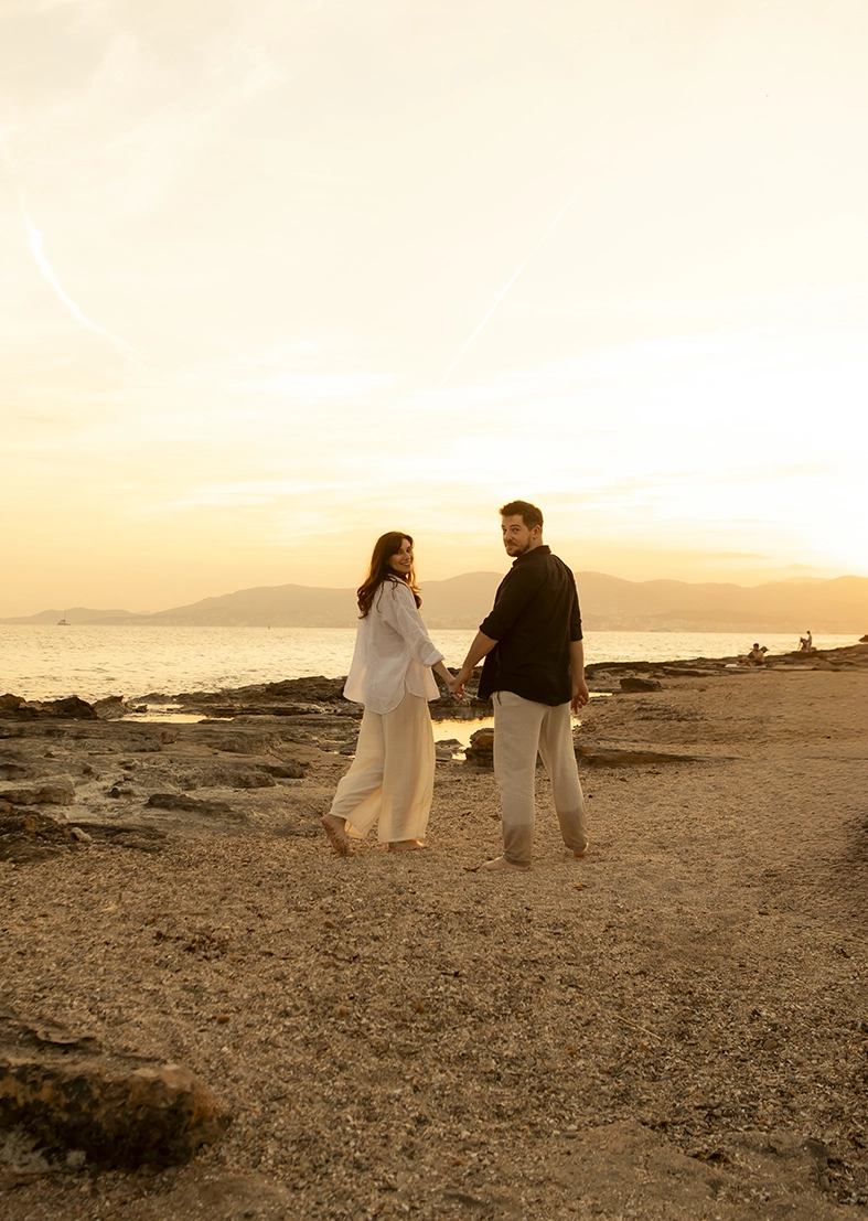 Couple walking hand in hand by the sea at sunset in Mallorca.