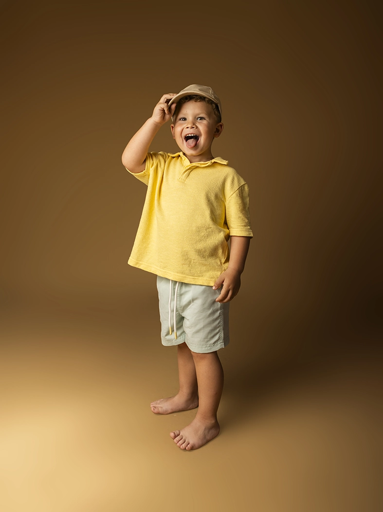 Child model Mallorca smiling and playing with a cap during a studio photoshoot by Inma del Valle.