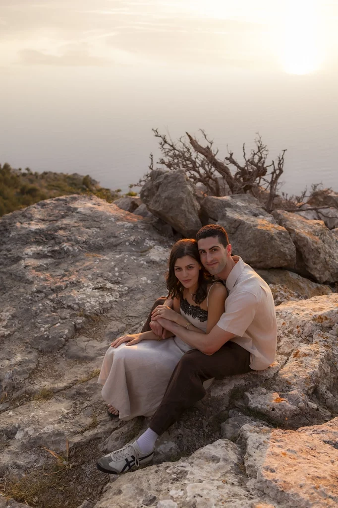 Engaged couple sitting on coastal rocks during an engagement photoshoot in Mallorca