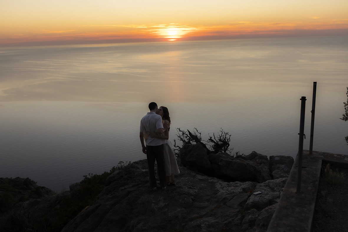 Engaged couple kissing at sunset during an engagement photoshoot in Mallorca overlooking the Mediterranean