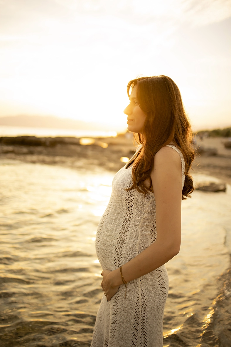 Futura mamá de perfil al atardecer junto al mar en Mallorca.