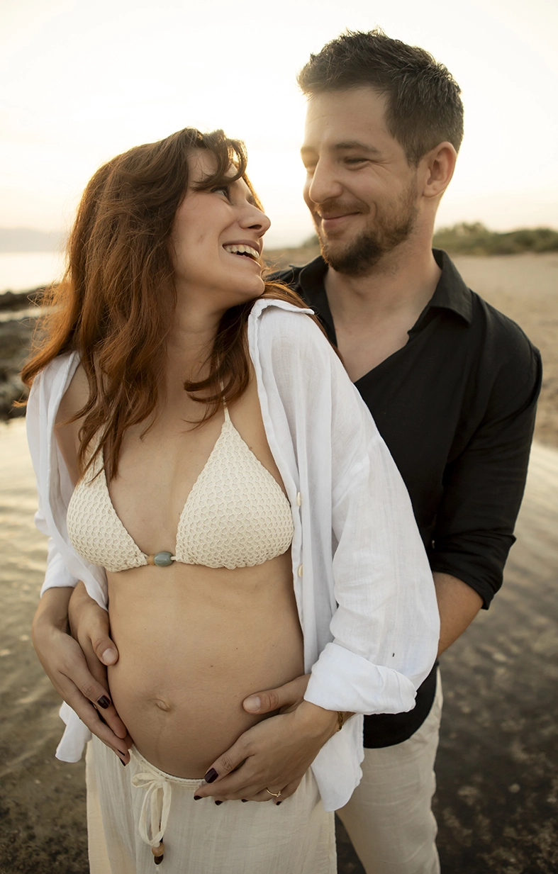 Pareja embarazada sonriendo al atardecer en Mallorca.