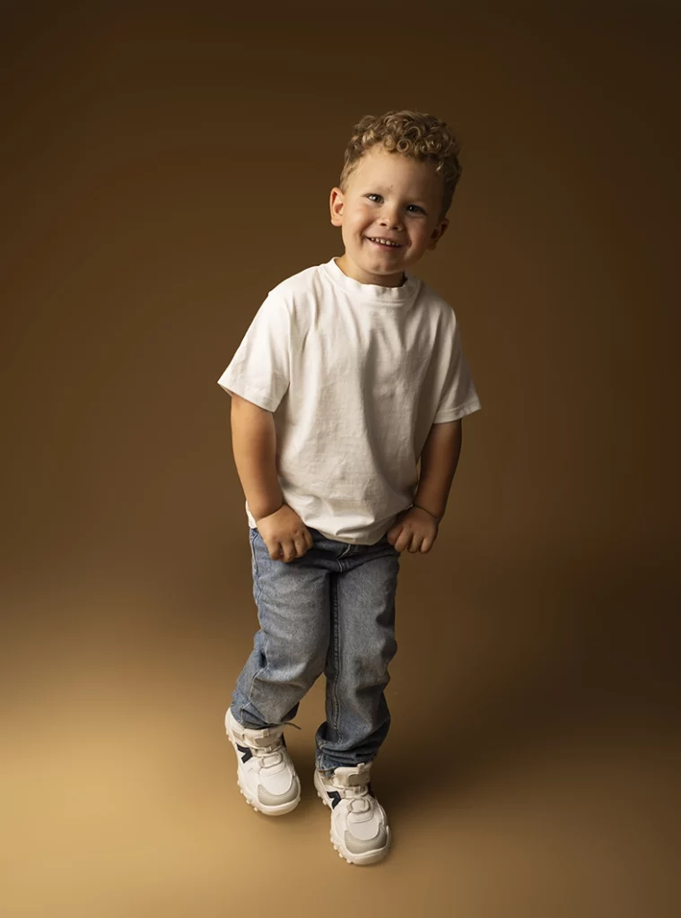 Modelo infantil Mallorca sonriendo de pie durante una sesión de estudio realizada por Inma del Valle.