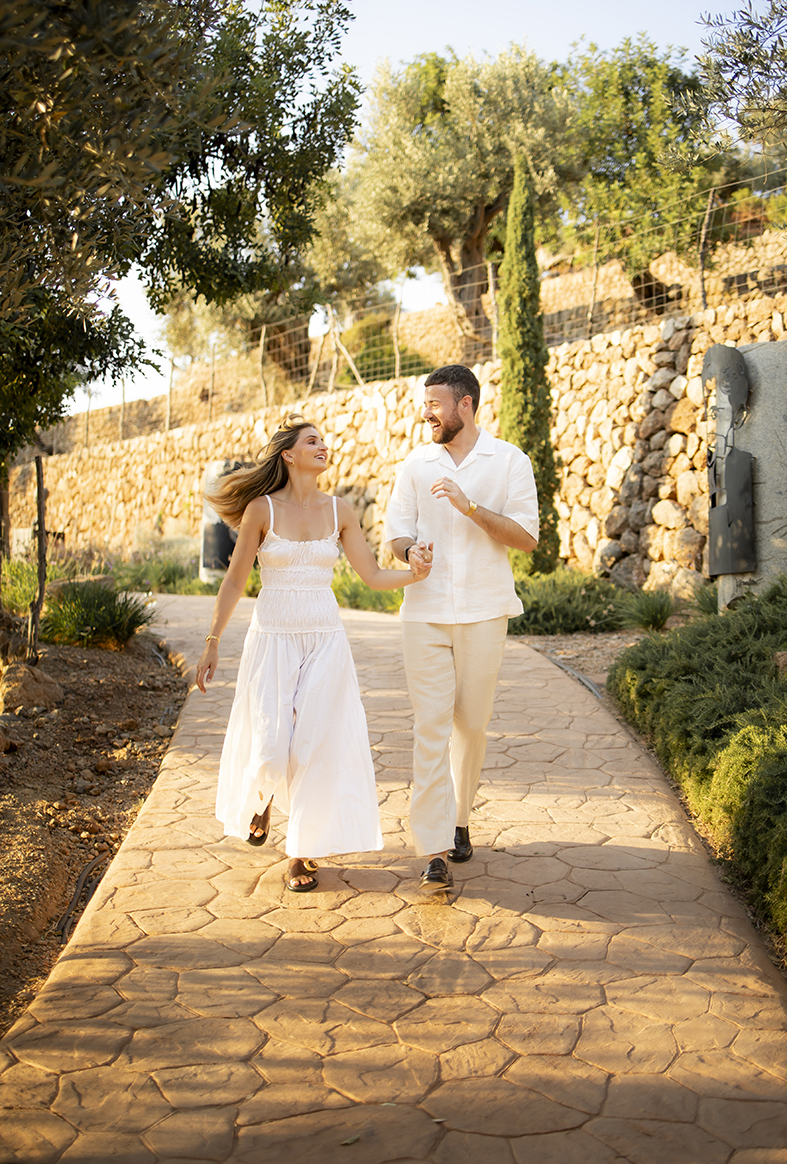 Ben and Scarlett walking happily through the gardens of Belmond La Residencia after their sunset proposal in Mallorca.
