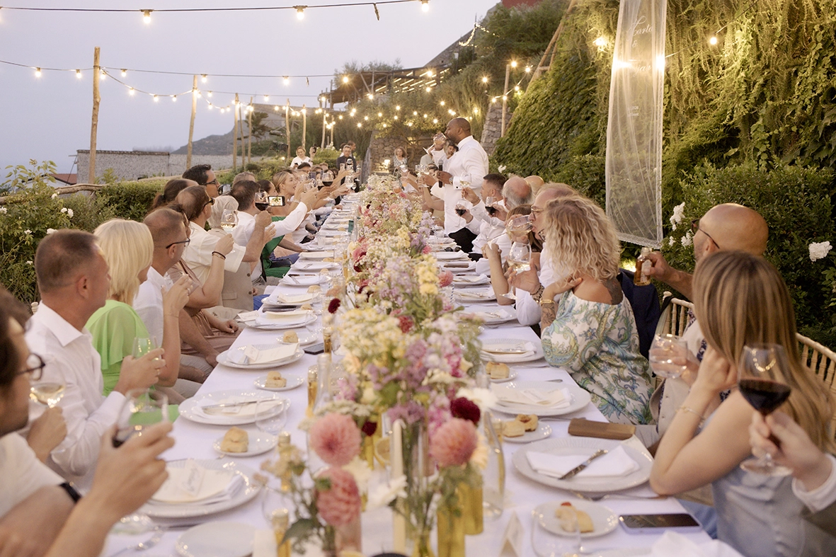 Invitados brindando durante una cena de boda al aire libre en la Costa Amalfitana.