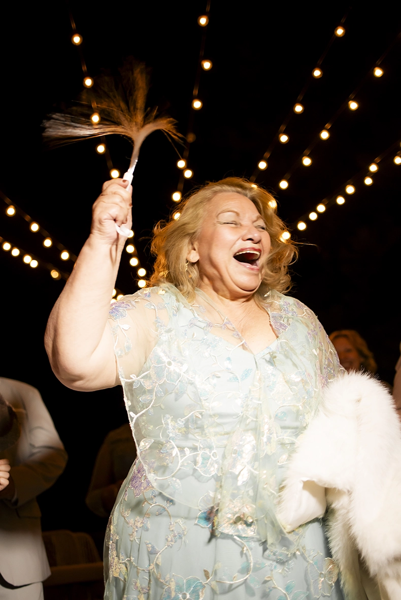Invitada riendo durante la fiesta de una boda en la Costa Amalfitana bajo una iluminación de guirnaldas.