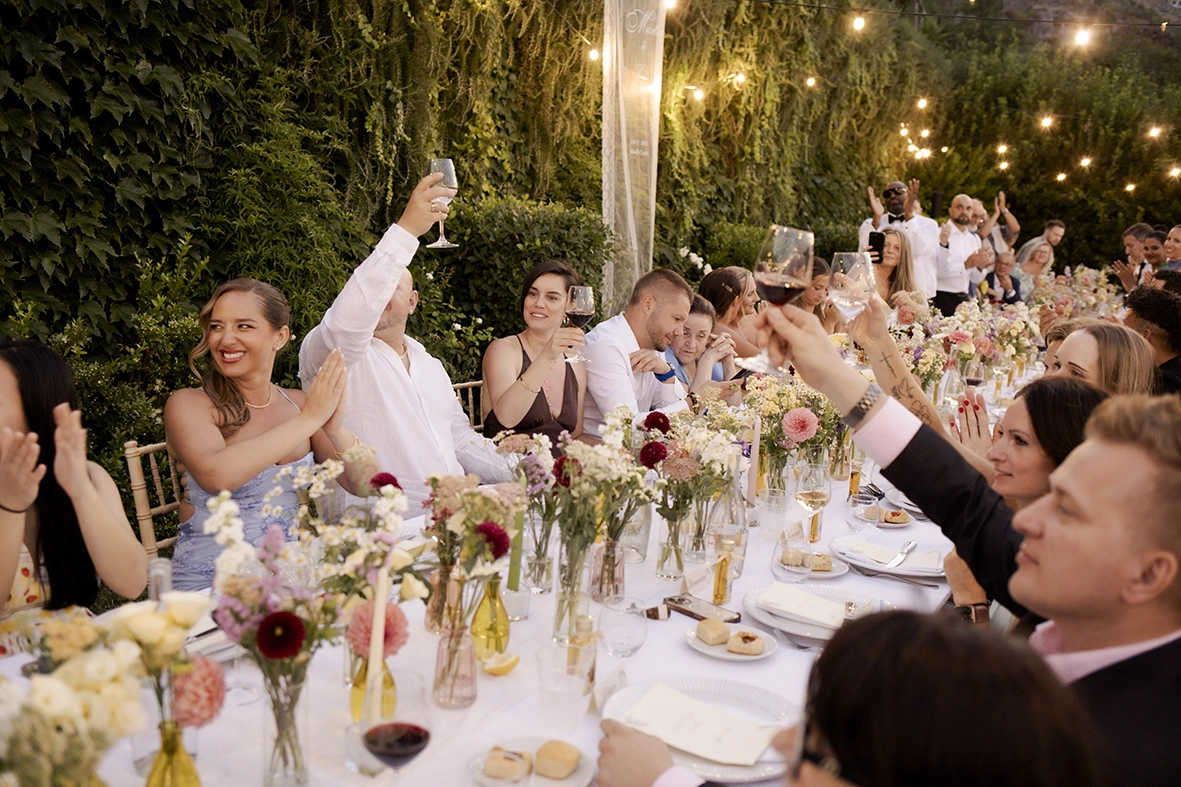 Invitados brindando durante la cena de una boda al aire libre en la Costa Amalfitana.