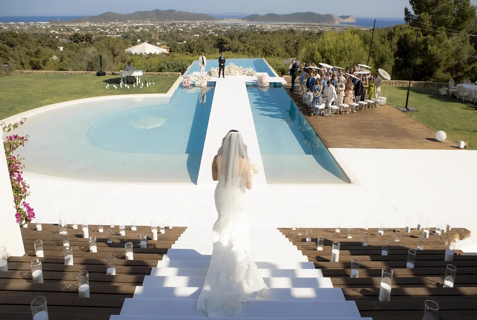 Novia caminando sobre una pasarela junto a la piscina durante una boda al aire libre en Mallorca.