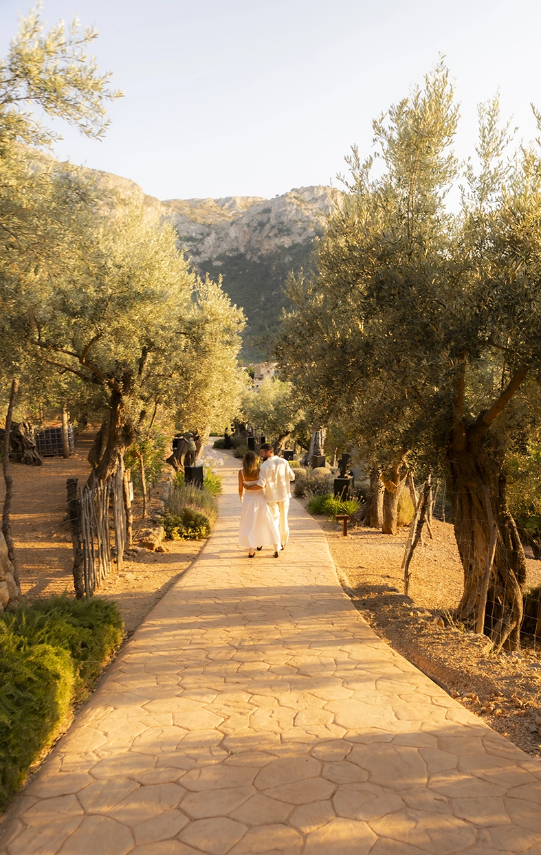 Pareja caminando abrazada por los jardines de Belmond La Residencia tras una pedida de matrimonio en Mallorca.