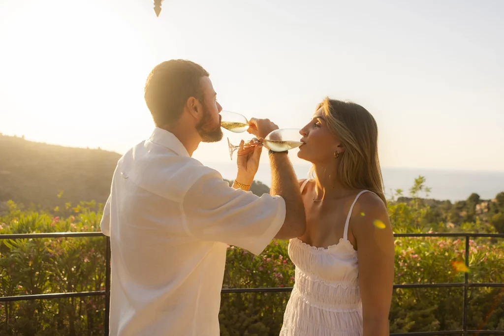 Pareja brindando con champán tras una pedida de mano en Belmond La Residencia durante la puesta de sol en Deià.