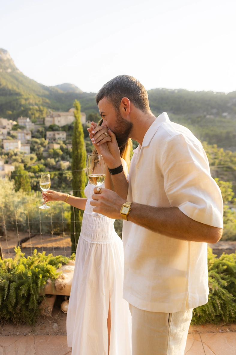 Novio besando la mano de su prometida después de una pedida de mano en Belmond La Residencia con vistas a Deià.