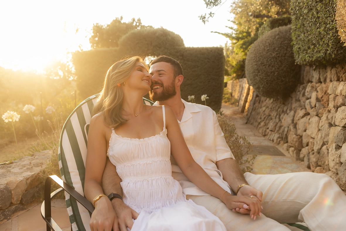 Pareja abrazada en una tumbona al atardecer en Belmond La Residencia después de una pedida de matrimonio en Mallorca.