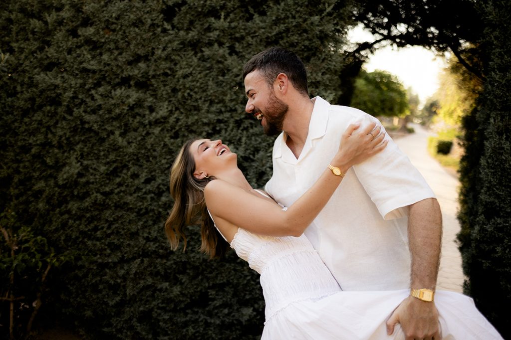 levanta a Scarlett mientras se besan bajo un arco de cipreses tras su pedida de matrimonio en Belmond La Residencia.