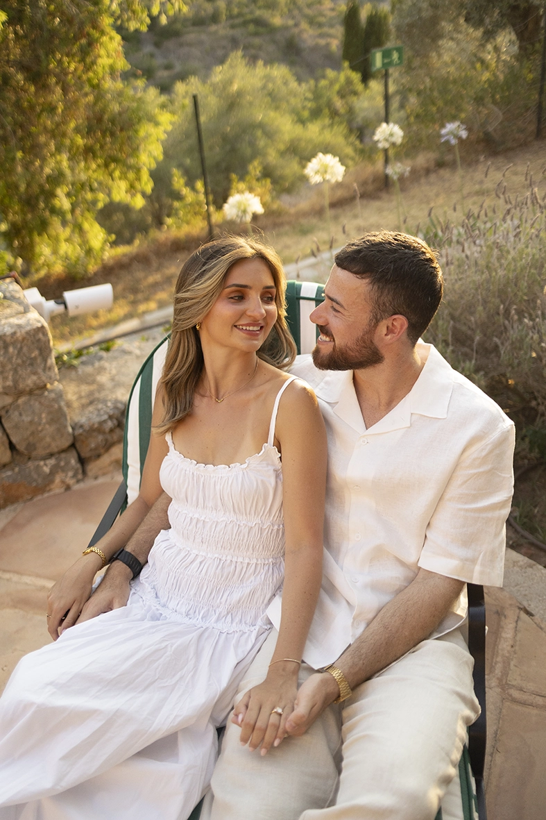 Pareja recién comprometida sentada en los jardines de Belmond La Residencia durante una sesión de fotos en Deià.