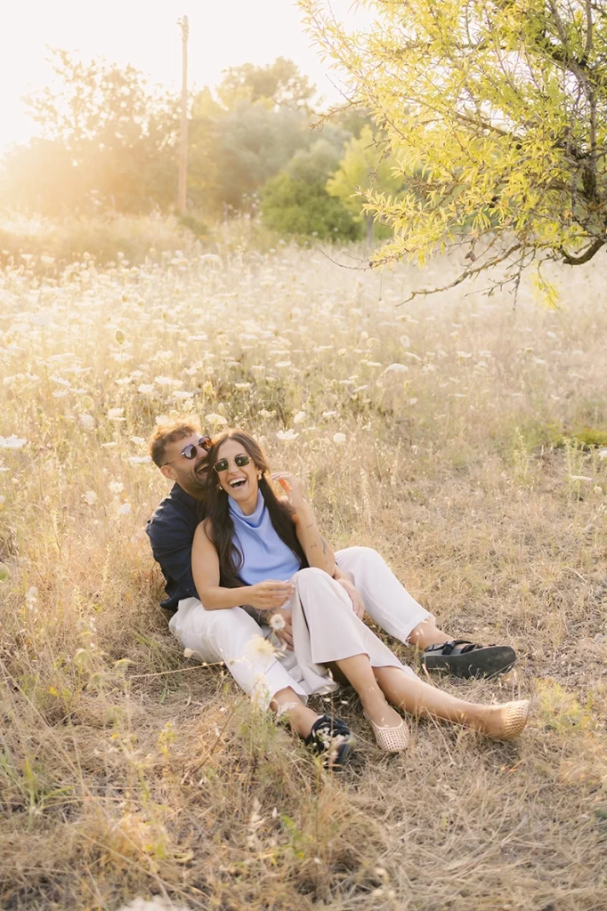 Anto and Biel sitting together among wildflowers during a sunset pre-wedding session.