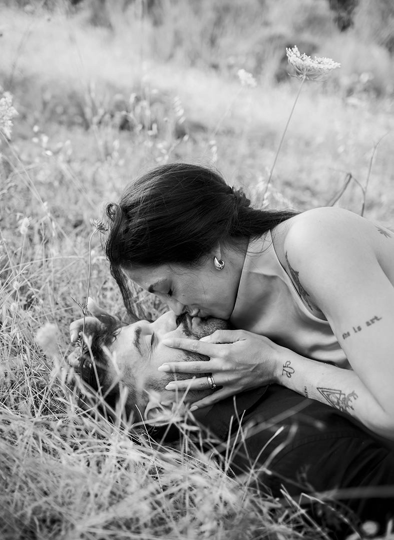 Anto kissing Biel while they lie in the grass during their pre-wedding session.