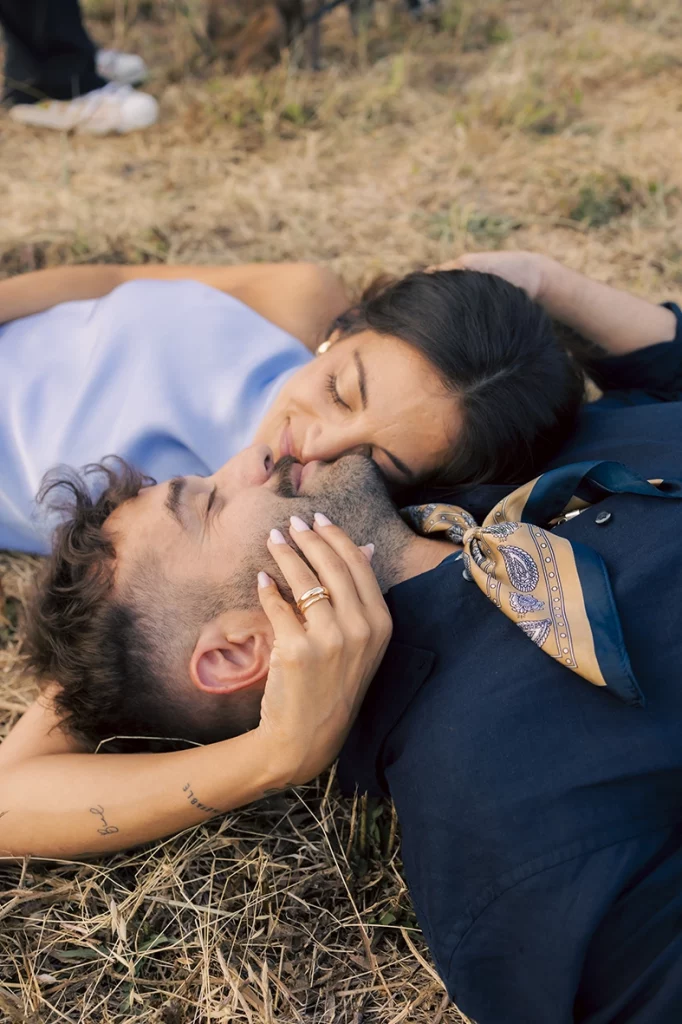 Anto besando a Biel mientras están tumbados en la hierba durante su sesión de preboda en Mallorca.