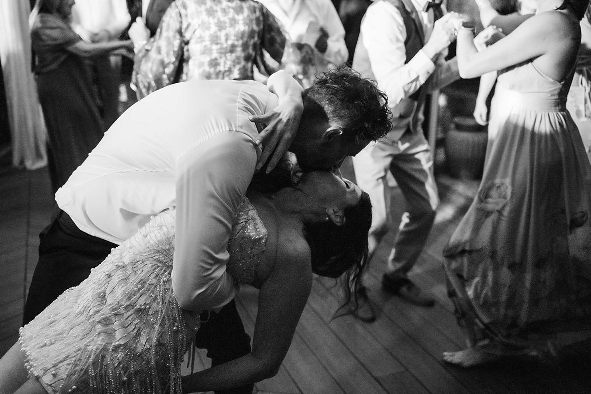 Black-and-white photograph of the newlyweds dancing together while guests celebrate around them.
